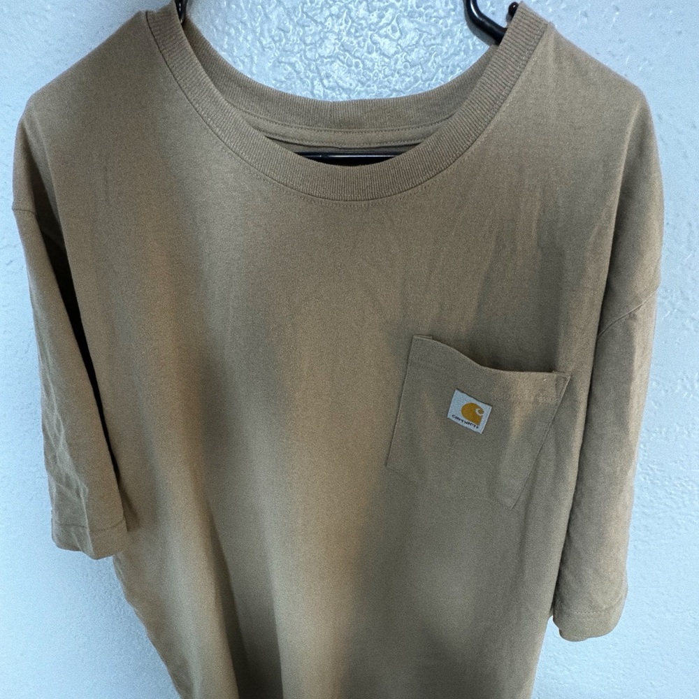 This is a men's Carhartt pocket t-shirt in a neutral tan perfect daily wear.